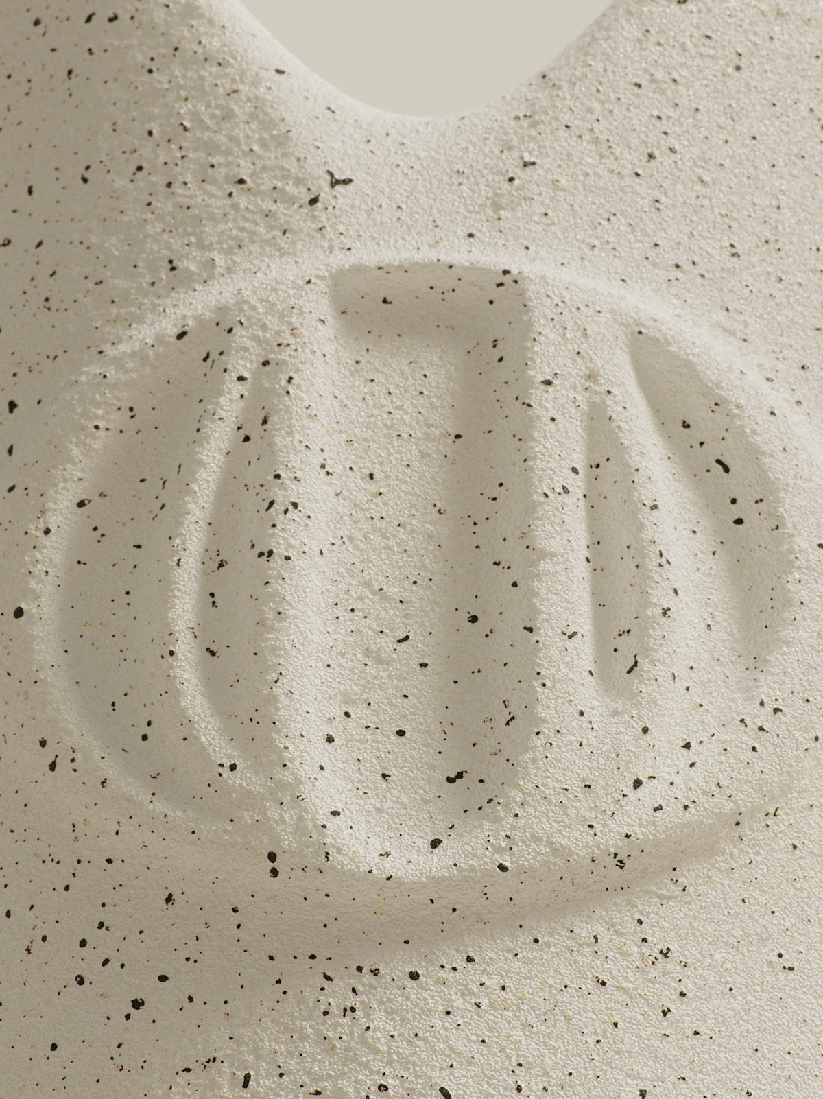 Imprint in sand with scattered black specks