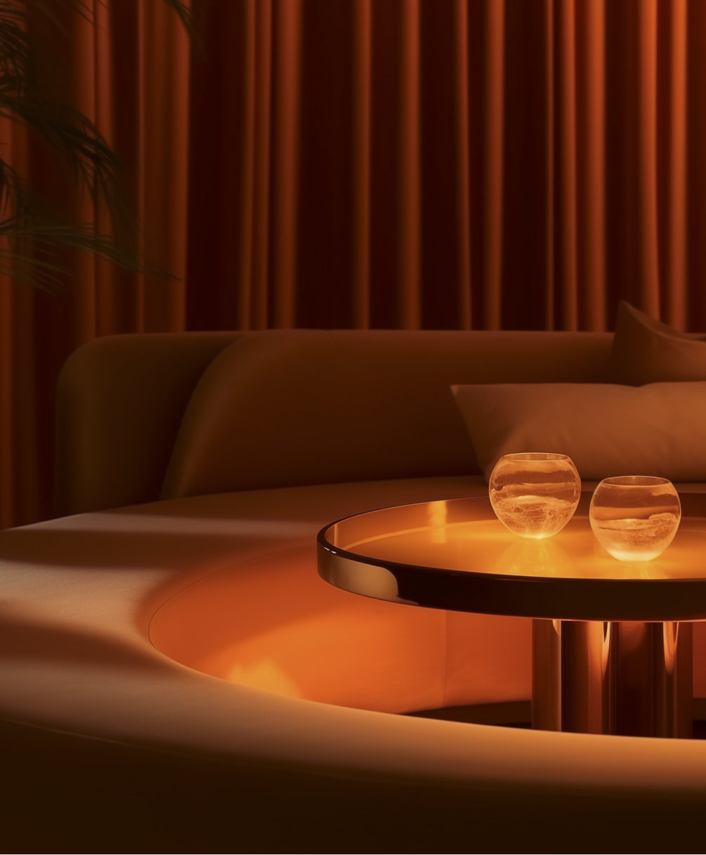 Warm lighting illuminates a cozy living space with a round table featuring two glass orbs